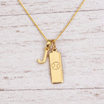 Gold Initial and Cancer Zodiac Necklace with letter J pendant on light wood