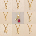 grid collection of gold fine chain necklaces with uppercase initial pendants R, S, T, U, A, V, W, X, Y on a light background, as personalised options on a July Birthstone Ruby Necklace.