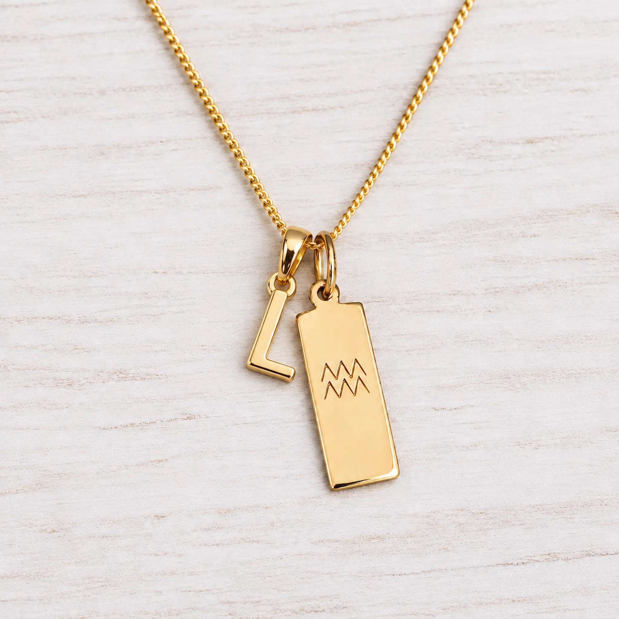 Gold Initial and Aquarius Zodiac Necklace with letter L pendant on light wood