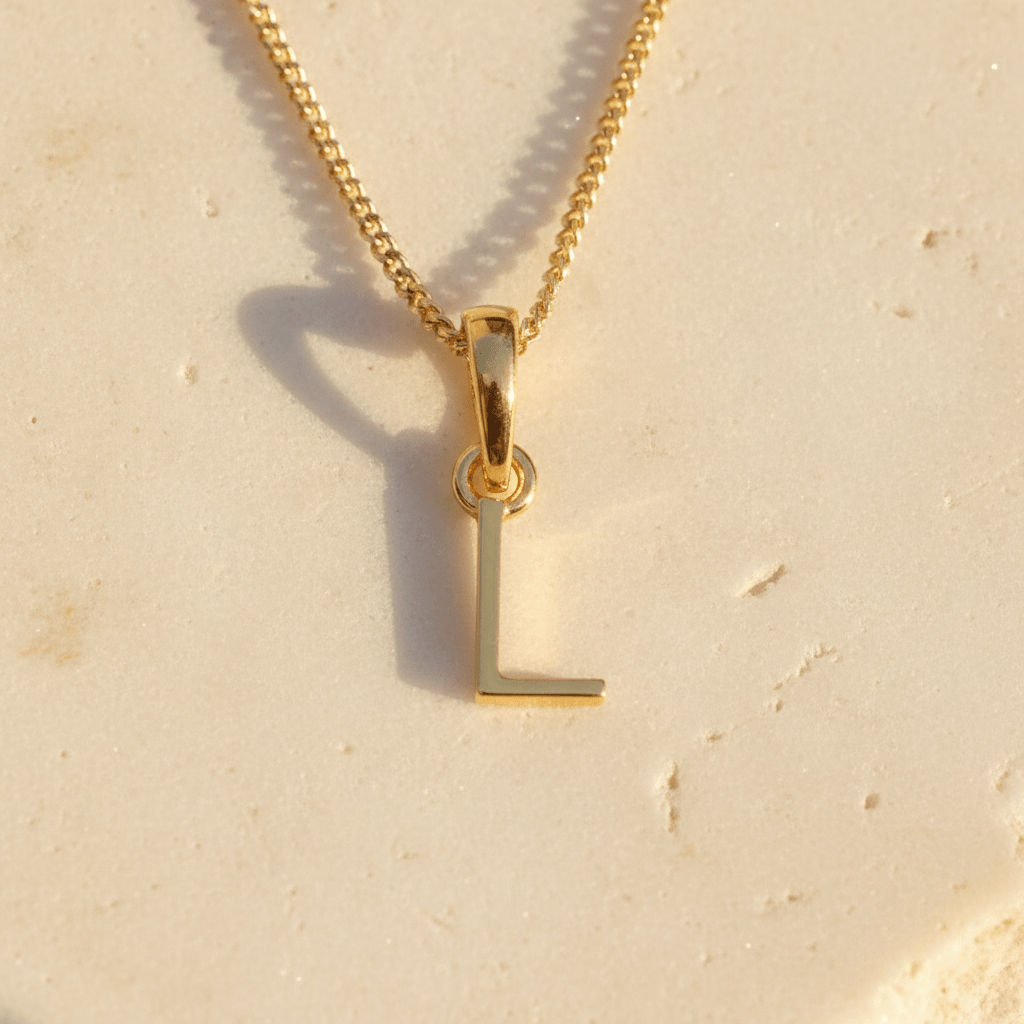 Gold necklace with a 'L' pendant on a beige background