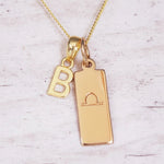 Gold necklace with 'B' pendant and libra zodiac sign on a light background
