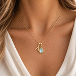 Model wearing a gold initial A and natural March aquamarine necklace with a soft ivory blouse
