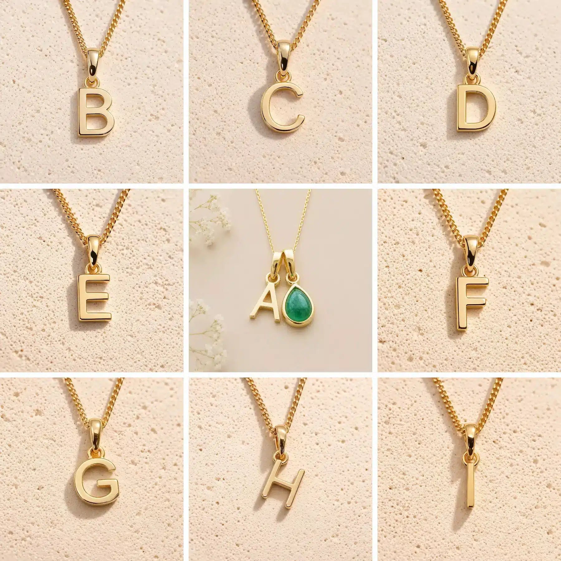 A 3x3 grid showing nine gold initial necklaces with letter pendants from A to I, displayed on a textured beige background. The center necklace features a gold letter A pendant paired with a green teardrop gemstone.