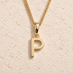Personalised Gold initial necklace with a minimalist 'P' pendant on a beige textured background
