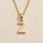 Personalised Gold initial necklace with a minimalist 'Z' pendant on a beige textured background