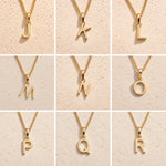 3 x 3 grid showing gold initial necklace charms J, K, L, M, N, O, P, Q and R on fine cable chains against a beige stone background, showing personalised letter options for the libra zodiac necklace