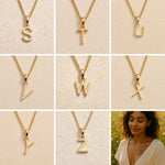 3 x 3 grid showing gold initial necklace charms S, T, U, V, W, X, Y and Z on fine cable chains against a beige stone background, showing personalised letter options for the Leo zodiac necklace
