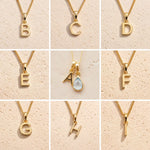 Gold necklaces with letters A to H on a beige background showing the personalised gold letters available for the November Birthstone Blue Topaz Necklace.