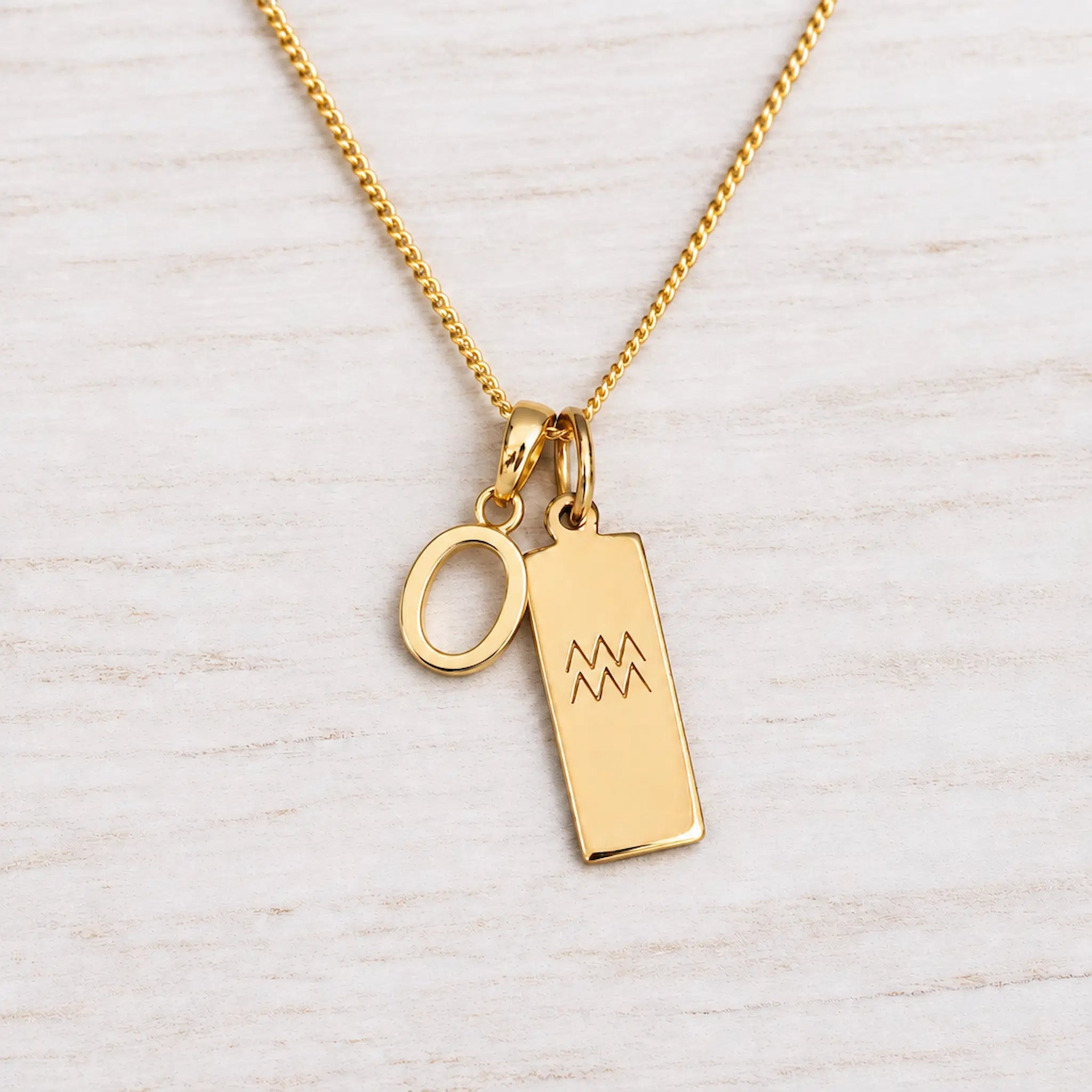 Gold Initial and Aquarius Zodiac Necklace with letter O pendant on light wood