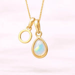 Gold October birthstone necklace with a pear-shaped natural opal pendant and letter 'O' charm with a light background.