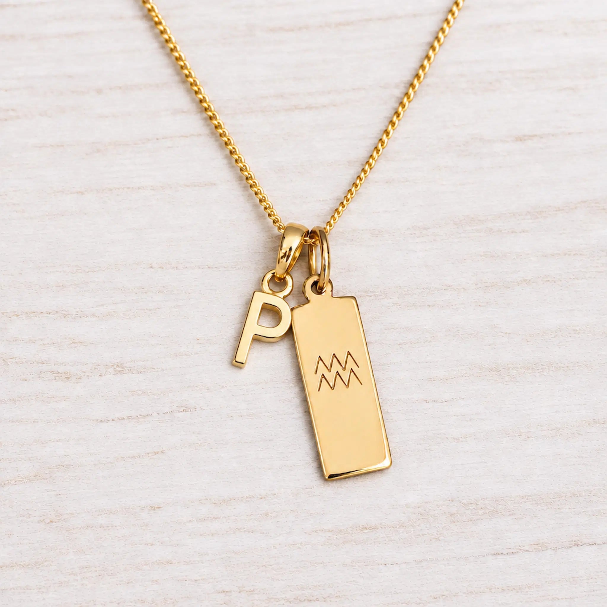 Gold Initial and Aquarius Zodiac Necklace with letter P pendant on light wood