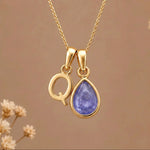 Gold Initial Q and December Birthstone natural Tanzanite Necklace on a warm background