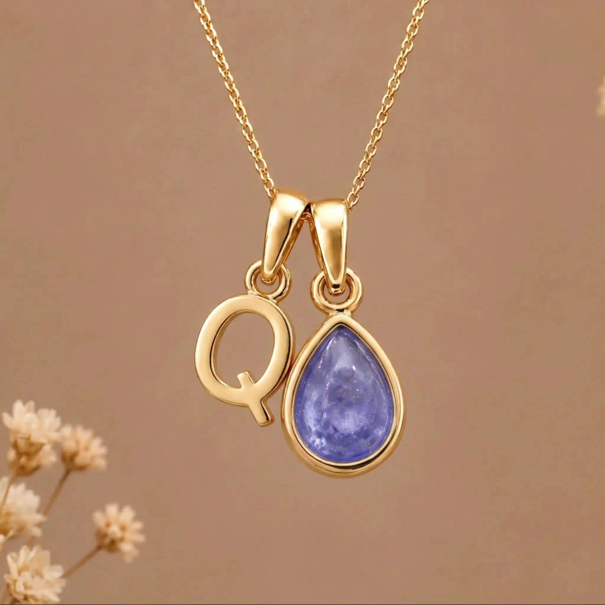 Gold Initial Q and December Birthstone natural Tanzanite Necklace on a warm background