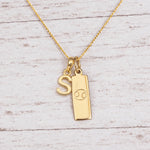 Gold Initial and Cancer Zodiac Necklace with letter S pendant on light wood