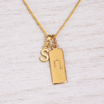 Gold Initial and Capricorn Zodiac Necklace with letter S pendant on light wood