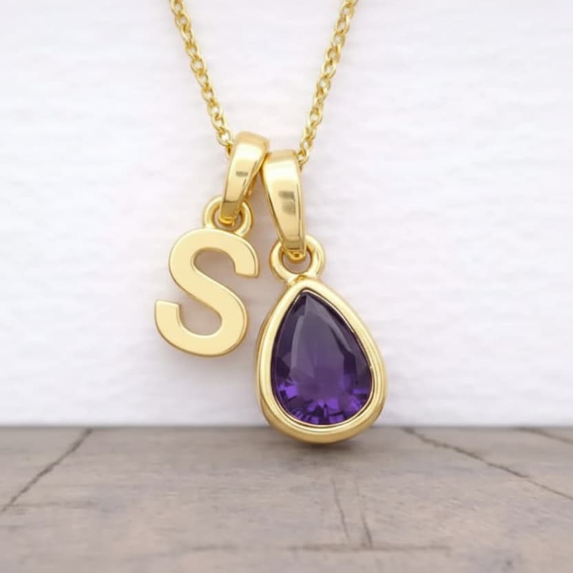 Gold necklace with 'S' pendant and purple teardrop pendant on a white background