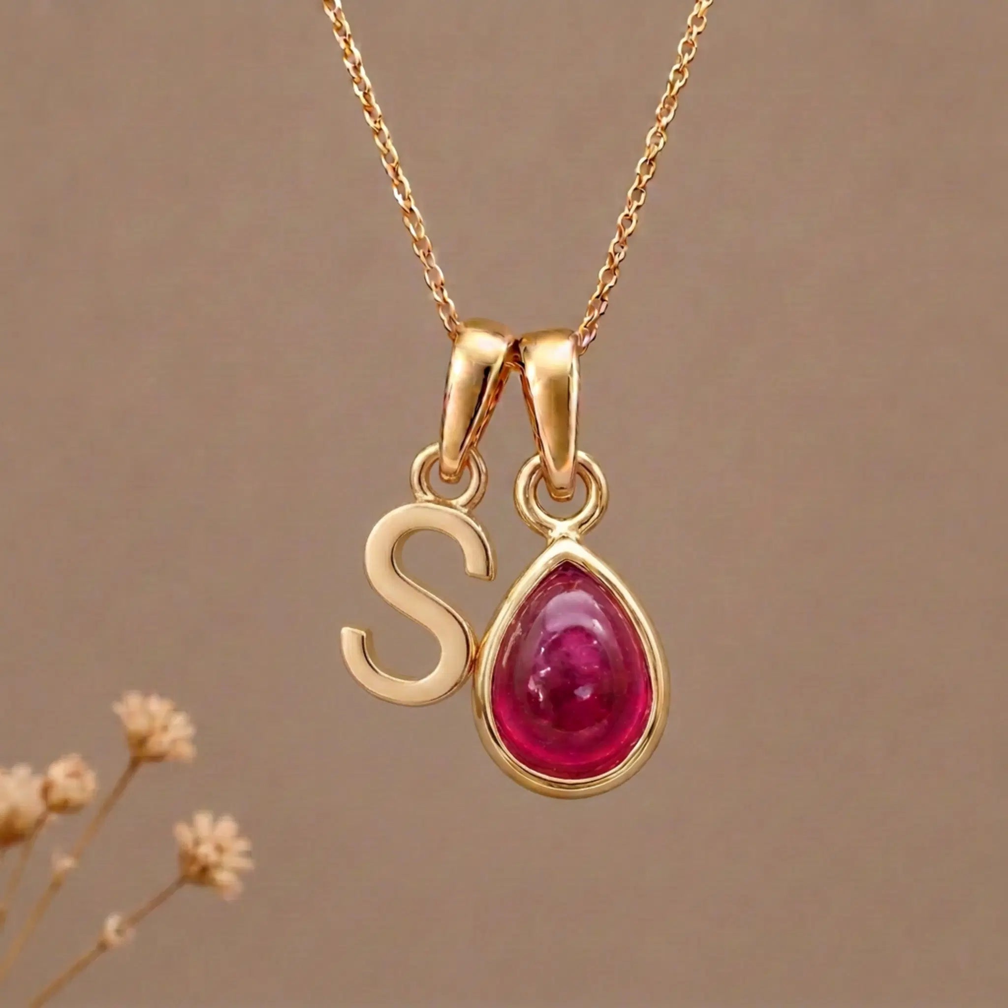 Gold Initial S Pendant and July birthstone Natural Ruby Necklace against a warm background