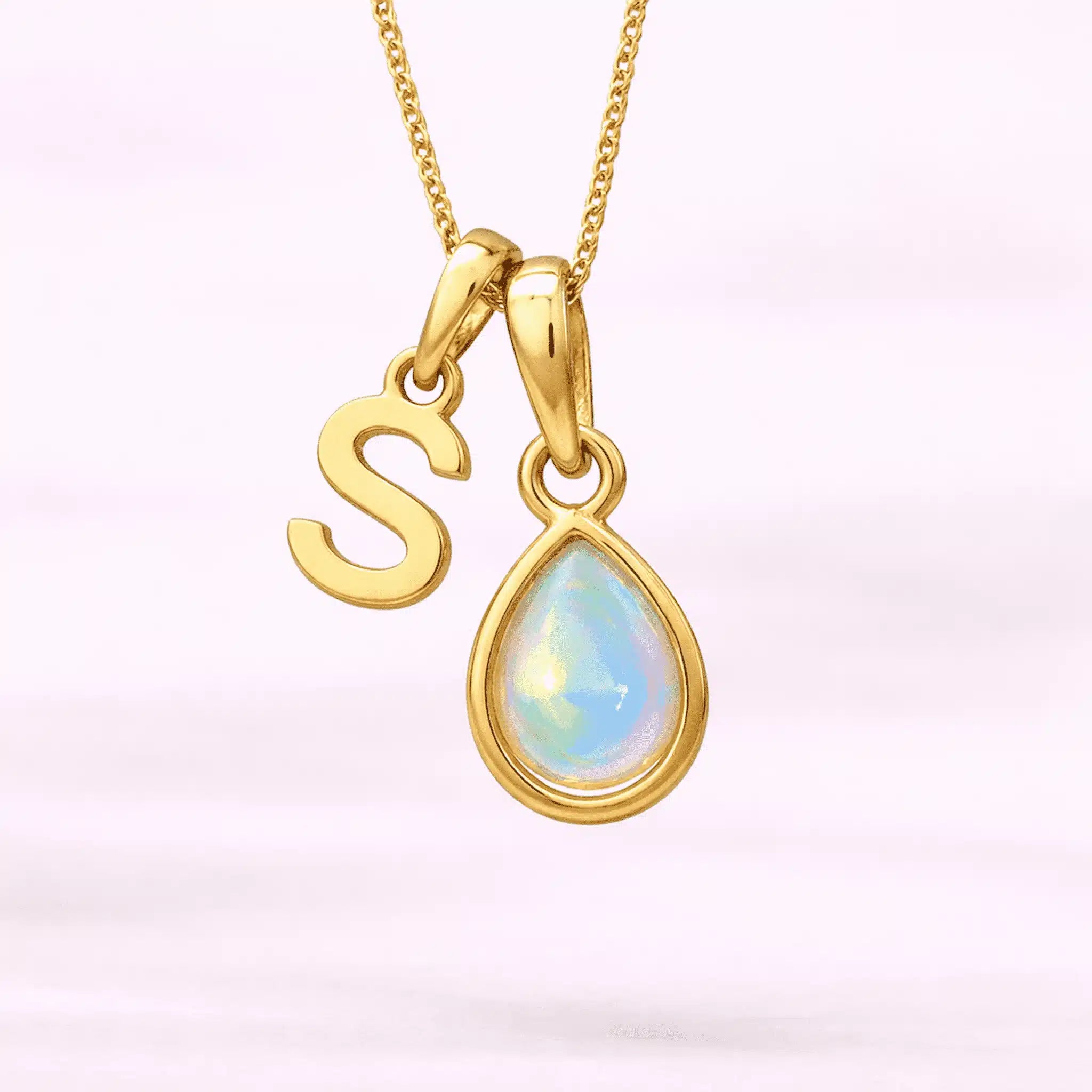 Gold October birthstone necklace with a pear-shaped natural opal pendant and letter 'S' charm with a light background.