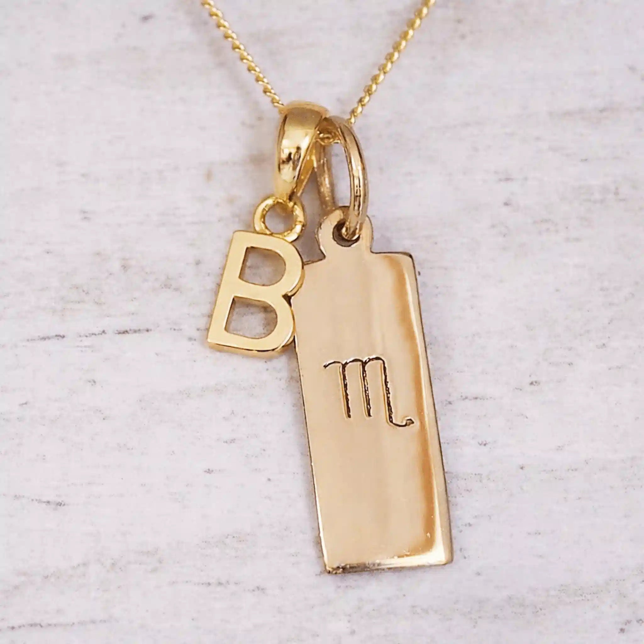 Personalised Gold double pendant necklace gift with a scorpio zodiac and B initial on a light background.