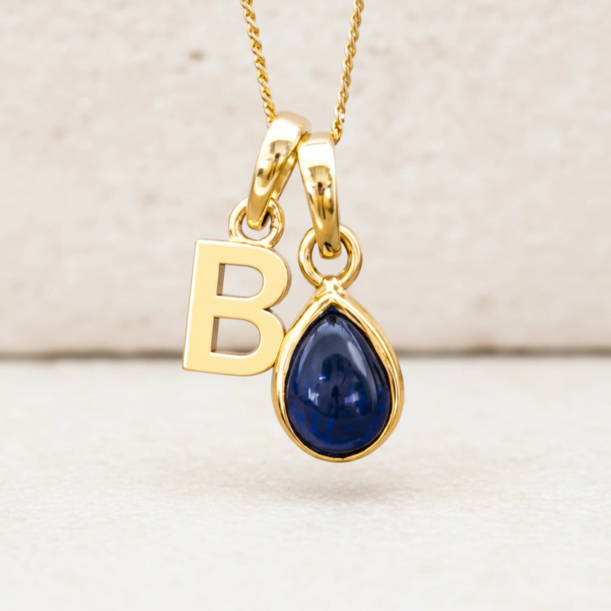 personalised Gold September birthstone necklace with 'B' initial pendant and blue sapphire teardrop gemstone 