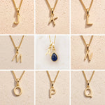 Grid of Gold Fine Chain Necklaces with uppercase letter pendants J, K, L, M, A, N, O, P, Q on a beige background, as personalised gold initial options to add to a September Birthstone Sapphire Necklace.