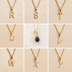 Grid of Gold Fine Chain Necklaces with uppercase letter pendants R, S, T, U, V, W, X, Y on a beige background, as personalised gold initial options to add to a September Birthstone Sapphire Necklace.