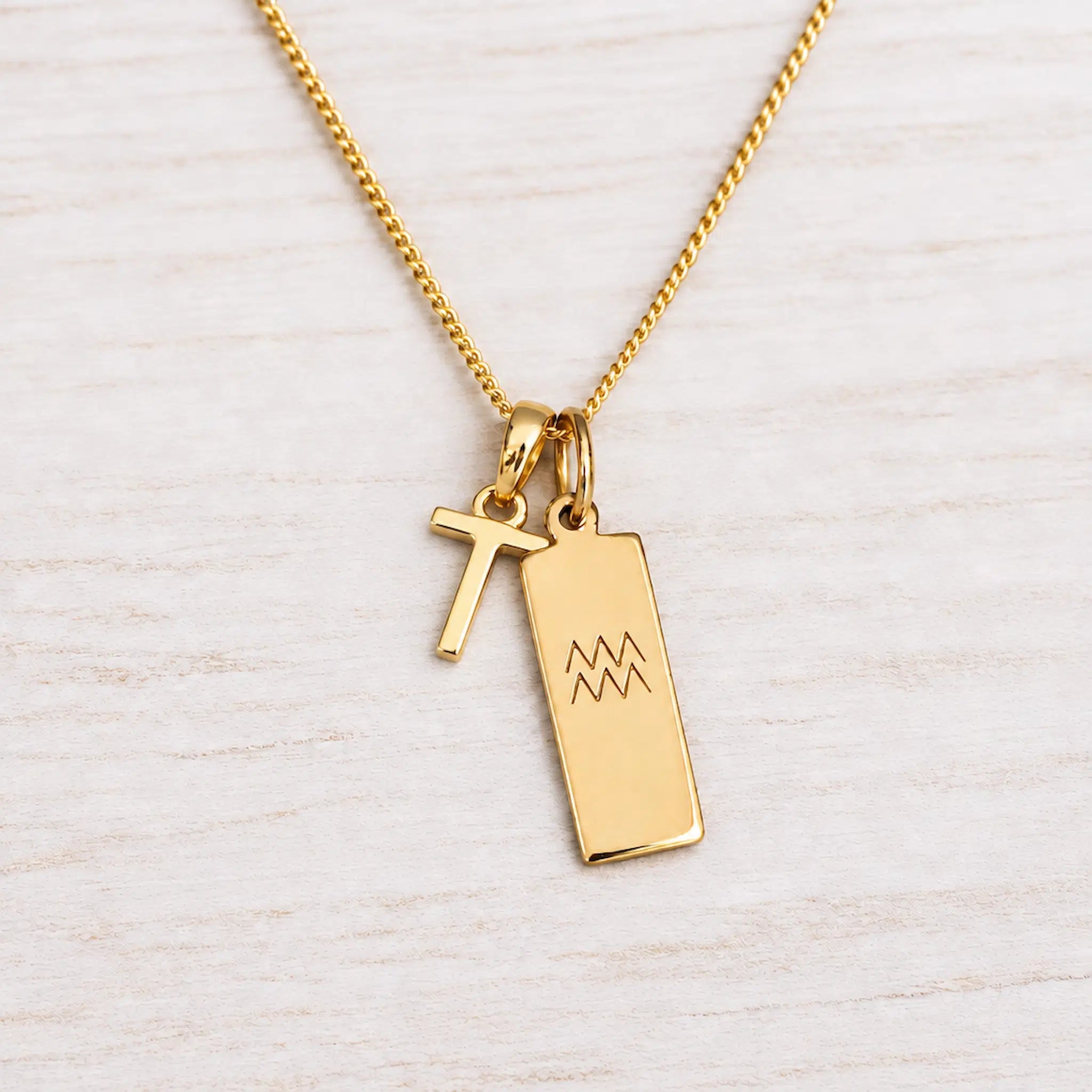 Gold Initial and Aquarius Zodiac Necklace with letter T pendant on light wood