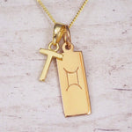 Gold initial T and Gemini zodiac bar necklace, close-up of the letter charm and engraved pendant on whitewashed wood