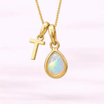 Gold October birthstone necklace with a pear-shaped natural opal pendant and letter 'T' charm with a light background.