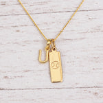 Gold Initial and Cancer Zodiac Necklace with letter U pendant on light wood