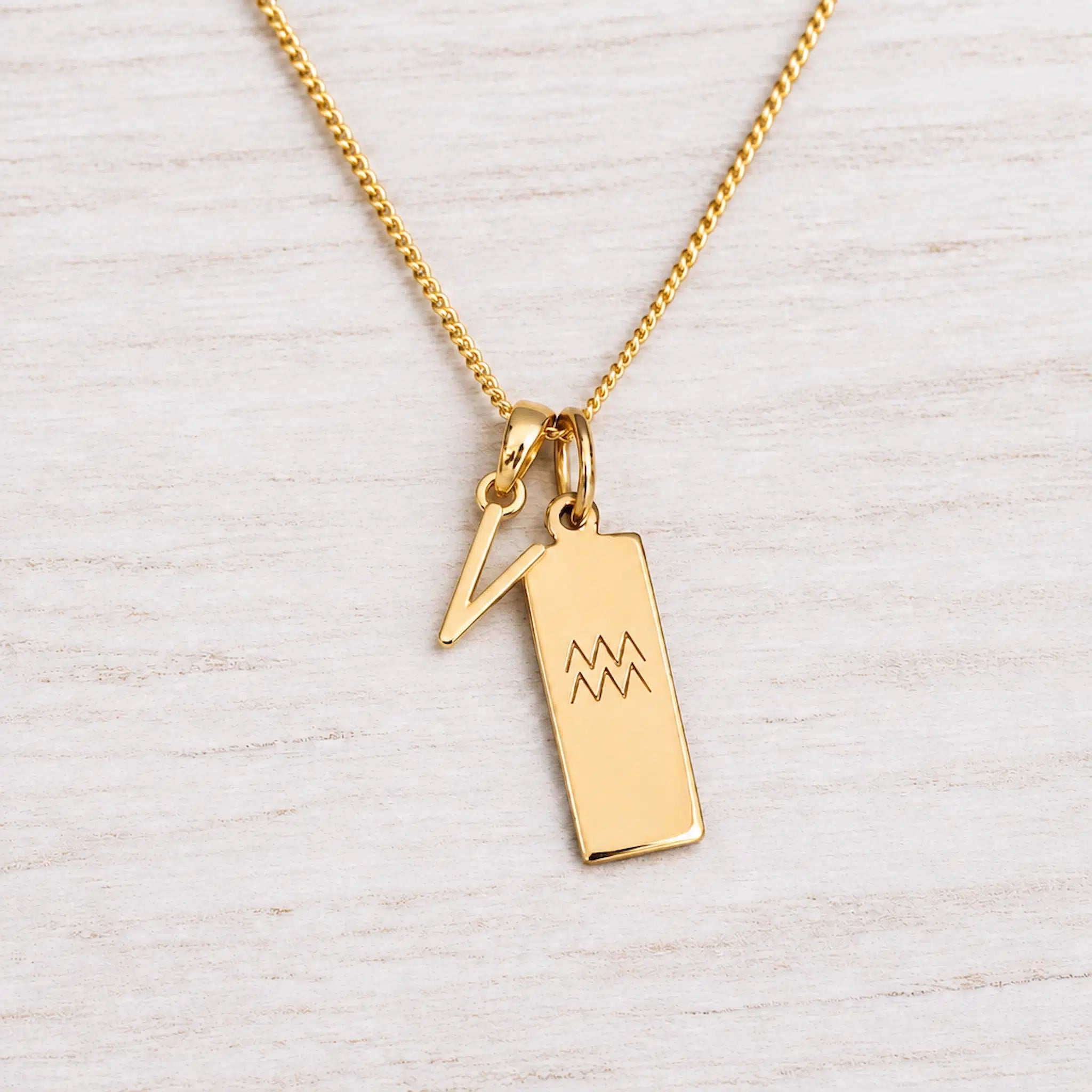 Gold Initial and Aquarius Zodiac Necklace with letter V pendant on light wood