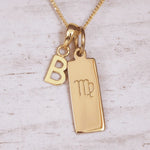 Gold necklace with 'B' initial pendant and Virgo zodiac sign on a light wooden background