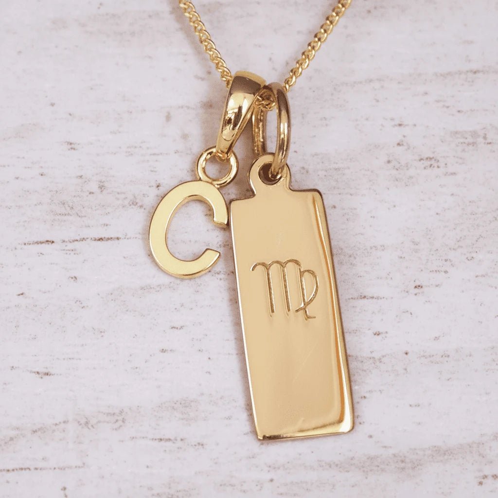 Gold necklace with 'C' initial pendant and Virgo zodiac sign on a light wooden background