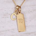 Gold necklace with 'C' initial pendant and Virgo zodiac sign on a light wooden background