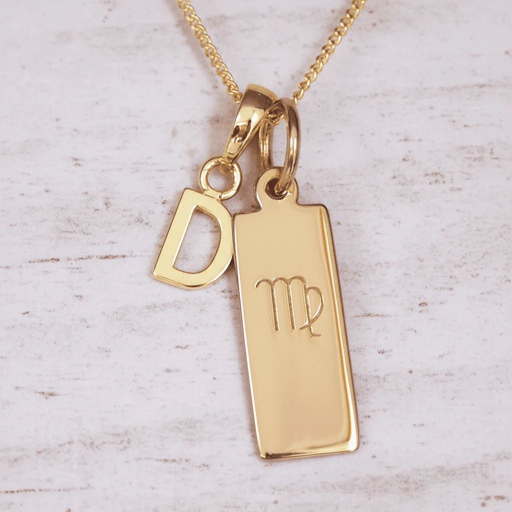 Gold necklace with 'D' initial pendant and Virgo zodiac sign on a light wooden background