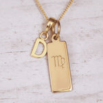 Gold necklace with 'D' initial pendant and Virgo zodiac sign on a light wooden background