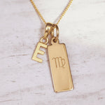 Gold necklace with 'E' initial pendant and Virgo zodiac sign on a light wooden background