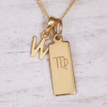 Gold necklace with 'W' initial pendant and Virgo zodiac sign on a light wooden background