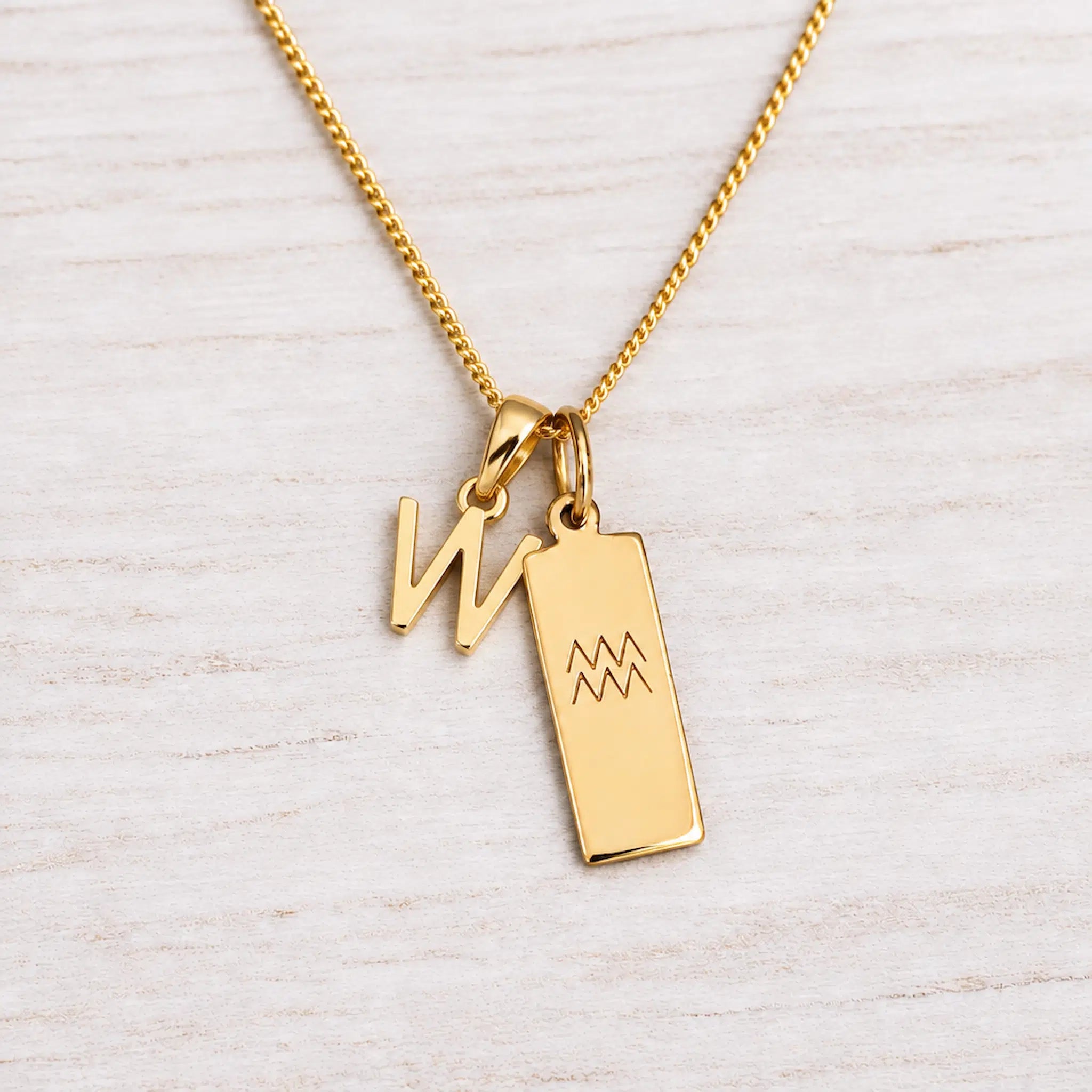 Gold Initial and Aquarius Zodiac Necklace with letter W pendant on light wood