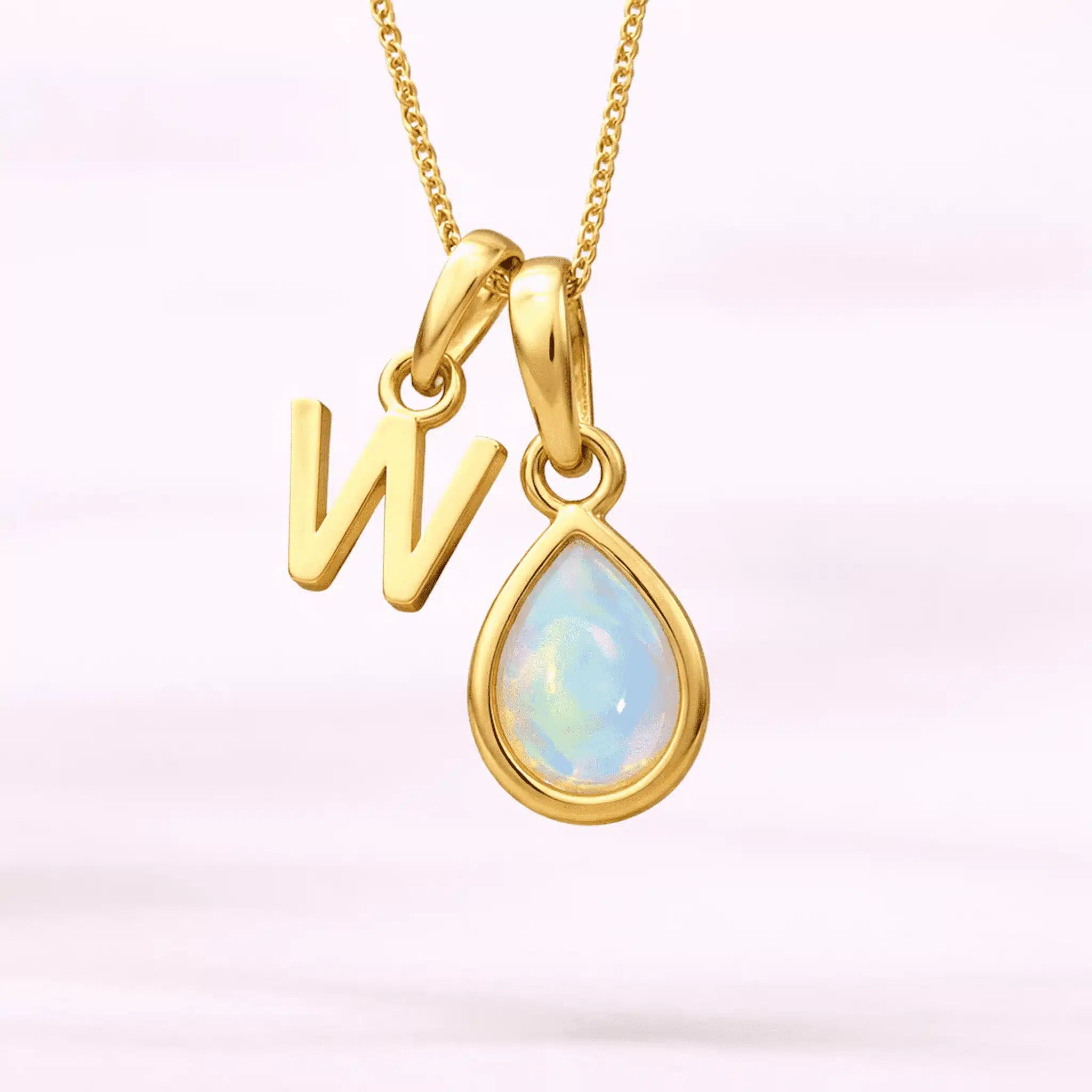 Gold October birthstone necklace with a pear-shaped natural opal pendant and letter 'W' charm with a light background.