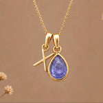 Gold Initial X and December Birthstone natural Tanzanite Necklace on a warm background