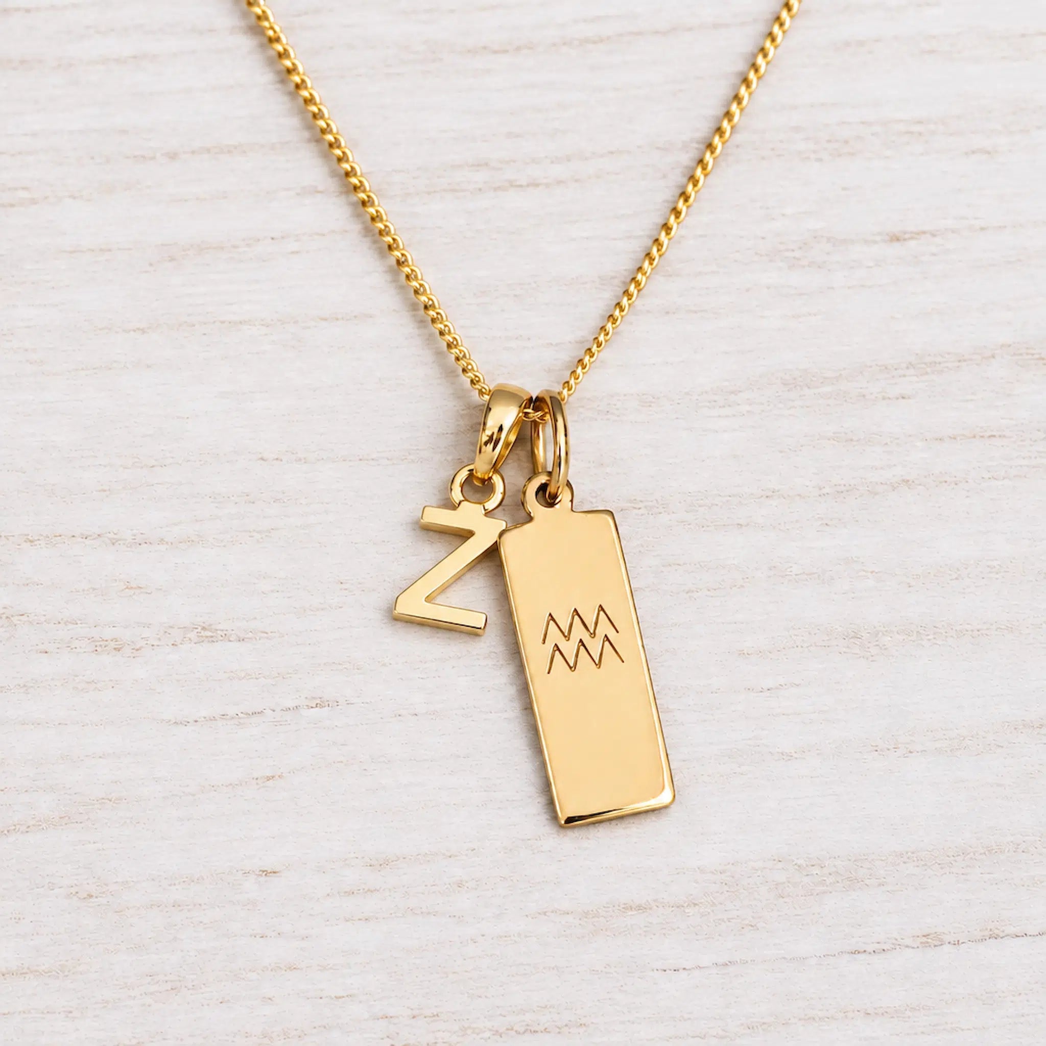 Gold Initial and Aquarius Zodiac Necklace with letter Z pendant on light wood