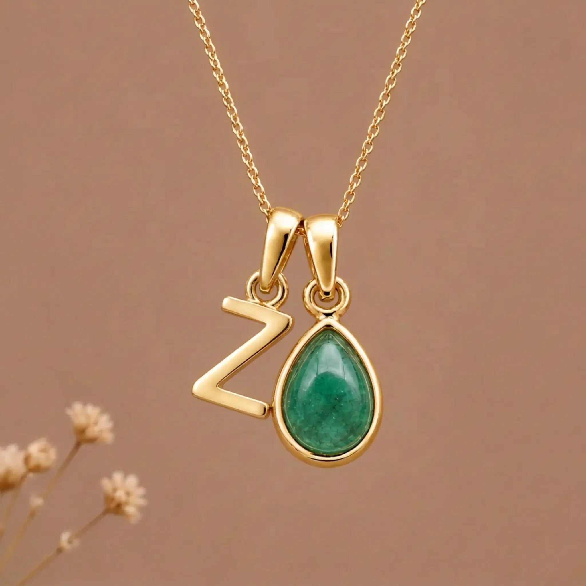 Gold Initial Z and May Birthstone Emerald Necklace against a warm background