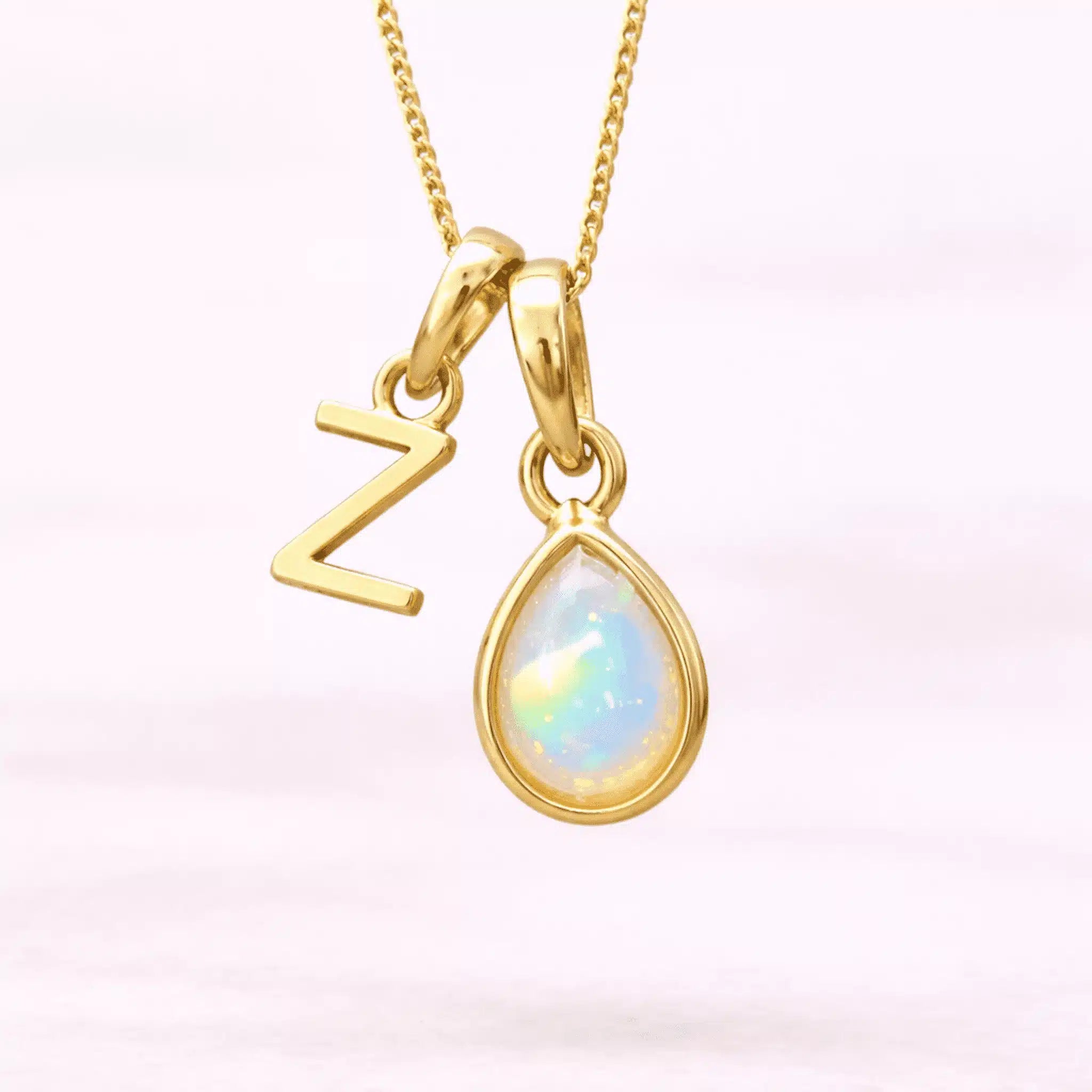 Gold October birthstone necklace with a pear-shaped natural opal pendant and letter 'Z' charm with a light background.