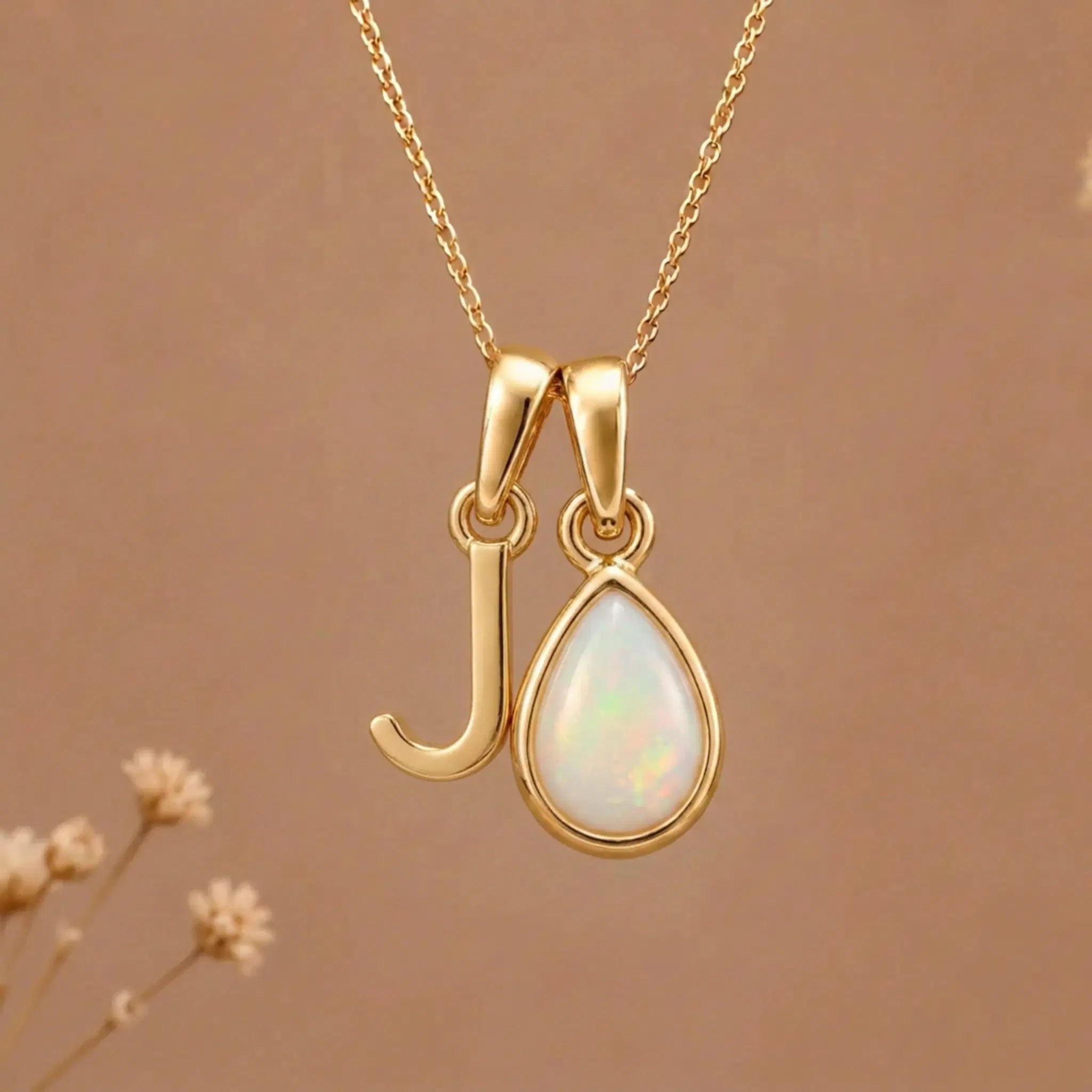 Gold Initial J Pendant and October birthstone Natural Opal Necklace against a warm background