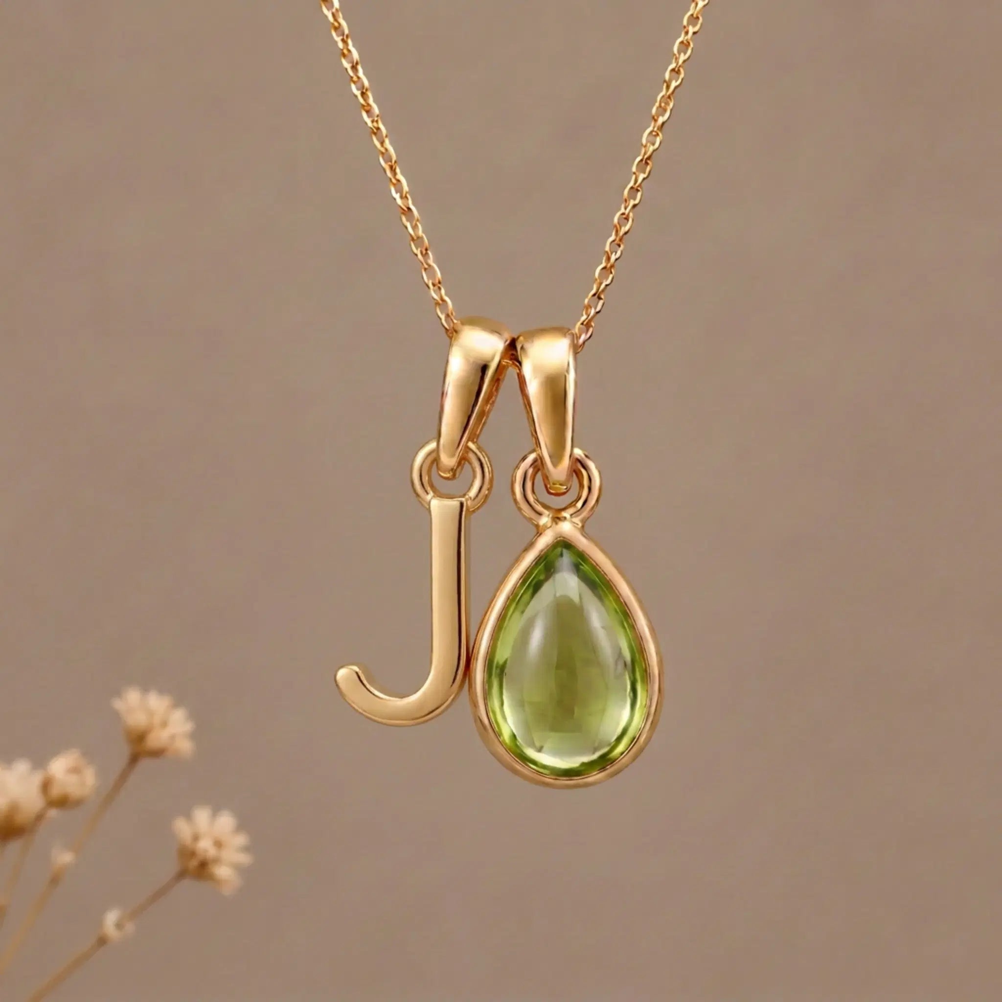 Gold Initial J Pendant and August birthstone Natural Peridot Necklace against a warm background