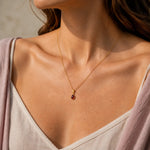 Model wearing a delicate gold January birthstone necklace with a small pear-shaped garnet pendant