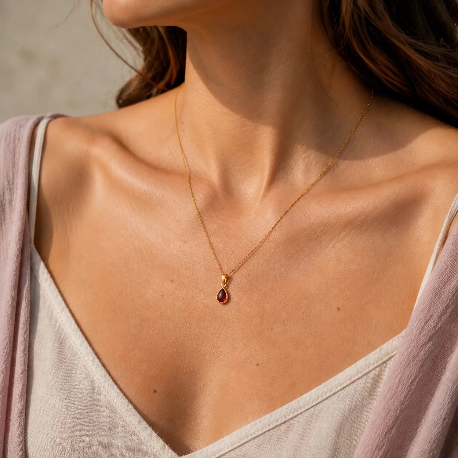 Model wearing a delicate gold January birthstone necklace with a small pear-shaped garnet pendant