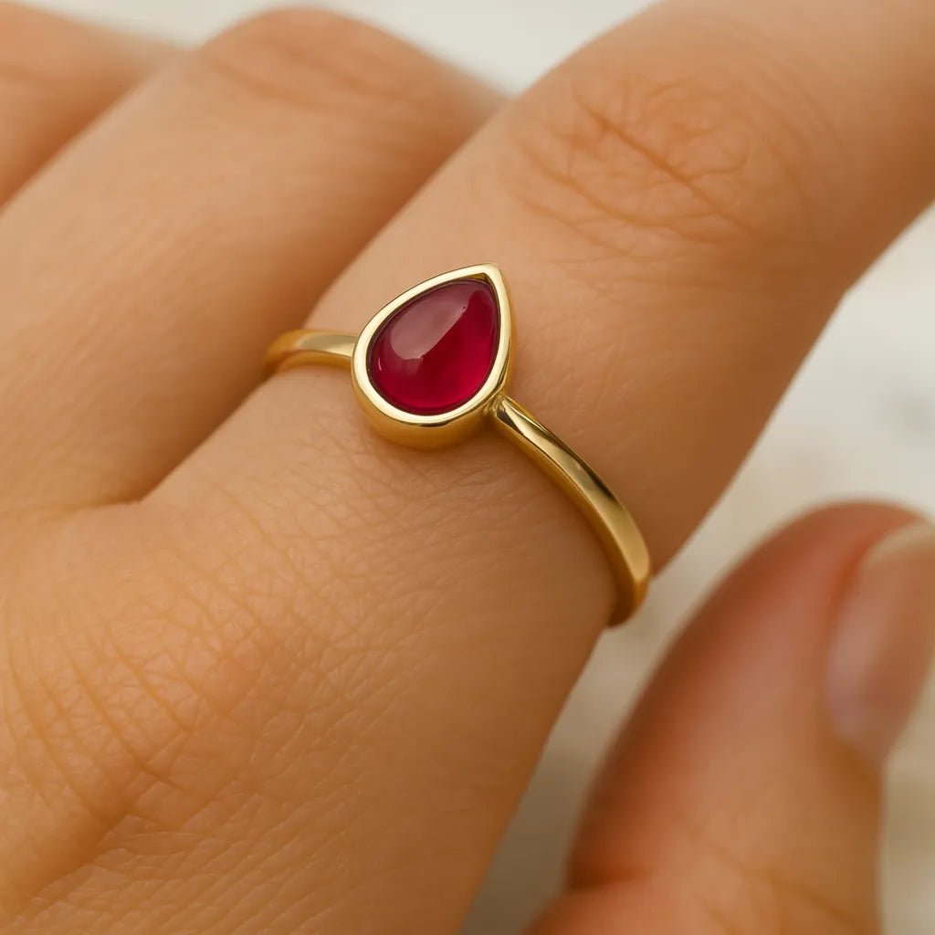 Gold January birthstone garnet ring worn on hand showing tear drop garnet stone