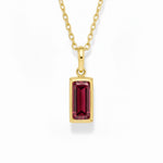 gold january birthstone necklace with red cubic zirconia on a white background.